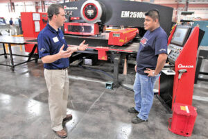 Nick Burrows, President Metalworking Solutions having discussion with an employee in front of the turrets.